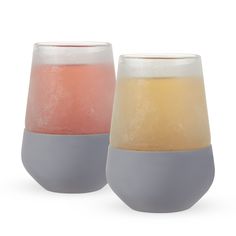 two glasses with different colored liquids sitting next to each other