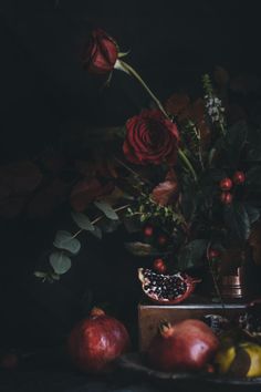 a still life with flowers, fruit and pomegranates on a table