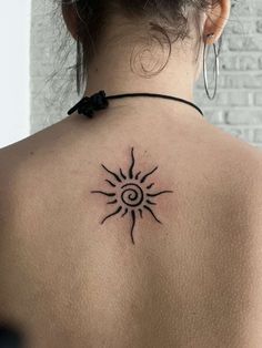 a woman's back with a sun tattoo on it