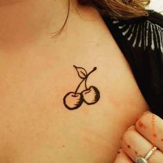 a small tattoo on the back of a woman's shoulder, with cherries