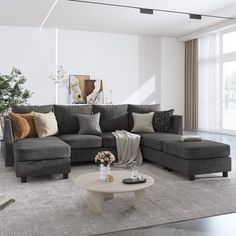 a living room with gray couches and pillows on the floor in front of a large window