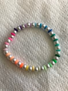 a bracelet with multicolored beads and white pearls on a white surface, in the shape of a circle