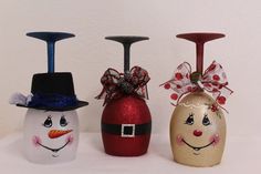 three wine glasses with painted faces on them and one has a candle holder in the shape of a snowman