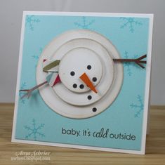 a card with a snowman made out of plates and carrots on it, sitting on a table