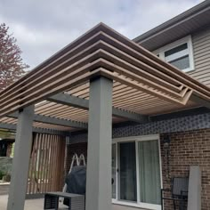 an outdoor patio covered with wooden slats and chairs next to a brick building on a cloudy day