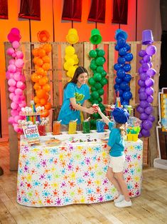 a woman and child standing in front of a table with balloons