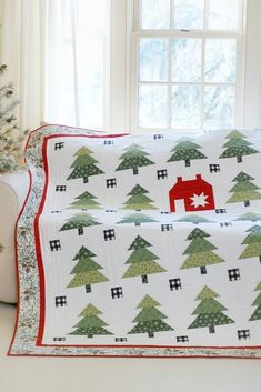 a white couch with a christmas tree quilt on it's side and a red house in the middle