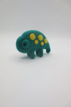 a small green and yellow stuffed animal on a white surface