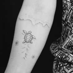 a woman's arm with a tattoo on it that has a turtle and flowers