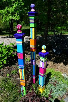 three tall colorful wooden sculptures in the grass