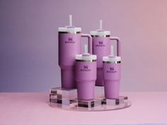 three purple tumblers sitting on top of a glass stand