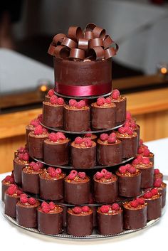 a large chocolate cake with raspberries on top is stacked high and ready to be eaten