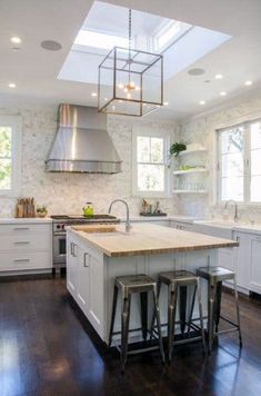 a kitchen with an island and two stools next to it, in front of windows