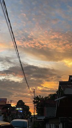 cars parked on the side of a road at dusk with clouds in the sky above