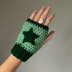 a hand wearing a green crocheted mitt with a star on it