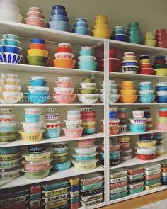 the shelves are full of colorful bowls and plates