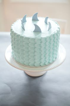 a blue cake with white frosting and two small gray birds on it's top