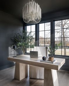 a laptop computer sitting on top of a wooden table next to a plant in a vase