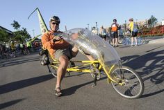 a man is sitting on a yellow bike with an inflatable bubble attached to it