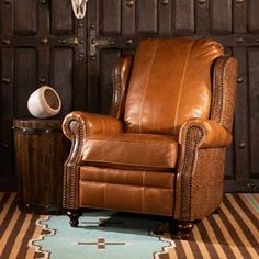 a brown leather recliner chair sitting on top of a rug