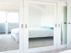 a bedroom with mirrored doors and white furniture