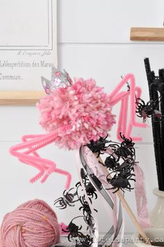 pink and black decorations are sitting on a table next to yarn, scissors and knitting needles