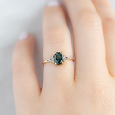 a woman's hand with a ring on it and a green stone in the middle