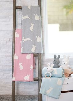 three towels hanging on a clothes rack next to a toy rabbit and other stuffed animals