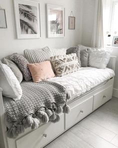 a white couch with lots of pillows and blankets on top of it's back