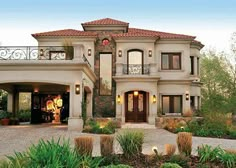 a large house with lots of windows and plants in front of the entrance to it