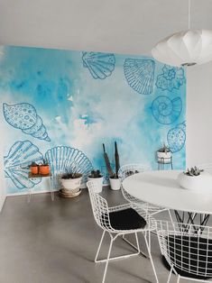 a white table and chairs in front of a blue wall with seashells painted on it