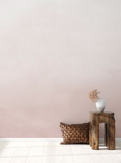 a white vase sitting on top of a table next to a wooden bench with a plant in it