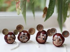 four wooden mice with faces painted on them sitting in front of a potted plant