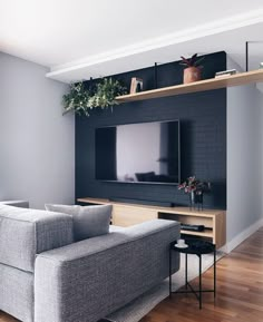 a living room with a gray couch and television on the wall, in front of a wooden entertainment center