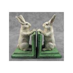 two white rabbits sitting on top of green bookends with their hands in each other's pockets