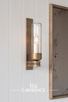 a wall light that is on the side of a wall with a mirror behind it