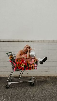 a woman sitting in a shopping cart with flowers on it