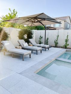 an outdoor pool with lounge chairs and an umbrella