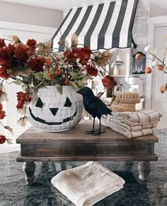 a black bird sitting on top of a table next to a vase filled with flowers