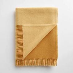 an orange and yellow blanket folded on top of a white surface with fringes around the edges