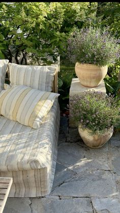 a couch sitting on top of a stone floor next to potted plants