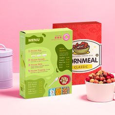 a box of cereal next to a bowl of cereal and a container of cereal on a pink background