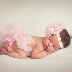 a baby girl is sleeping on her side wearing a pink tutu and headband