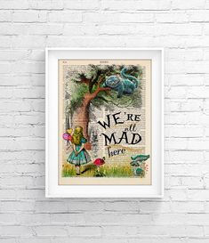 a framed book page with the words we're all mad in front of a tree