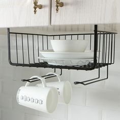 the kitchen sink has two cups and plates hanging from it's holder, which is attached to the wall