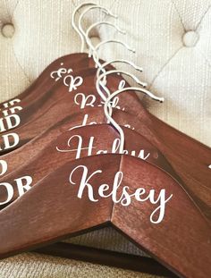 three wooden hangers with names on them sitting on a couch next to a pillow