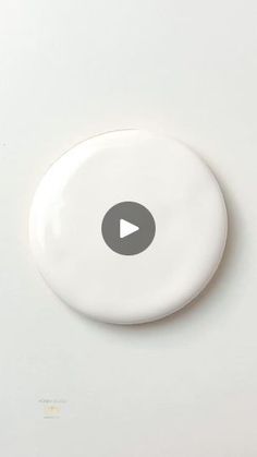 a white button with an arrow in the center on a white surface that says video