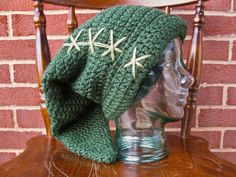 a crocheted green hat with white stars on it sitting on top of a wooden chair