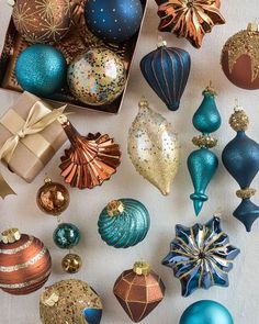 many different types of christmas ornaments are in a box on a tablecloth with gold and blue decorations