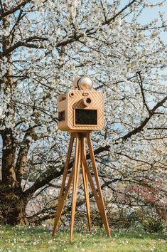 an old fashioned wooden camera on top of a tripod in front of a blooming tree